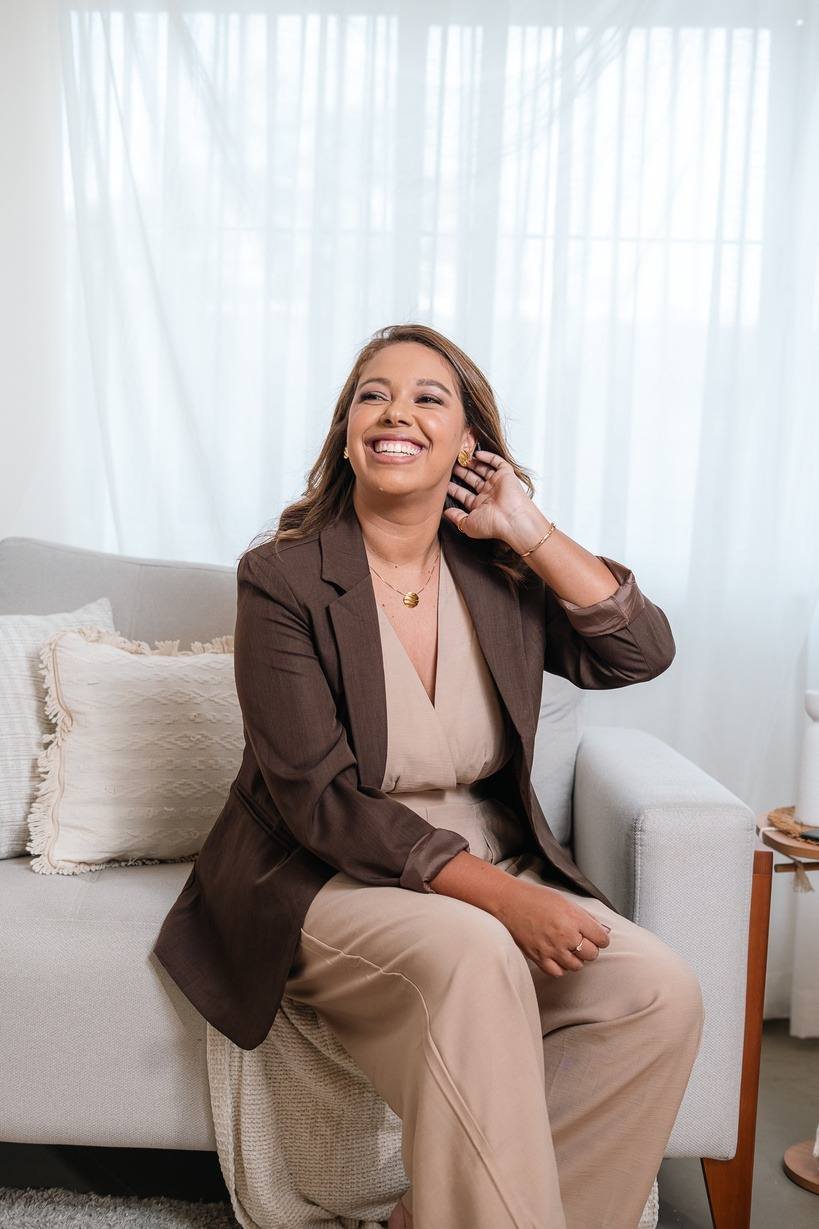 Jana Silva, assessora de casamentos, sorrindo em um sofá claro