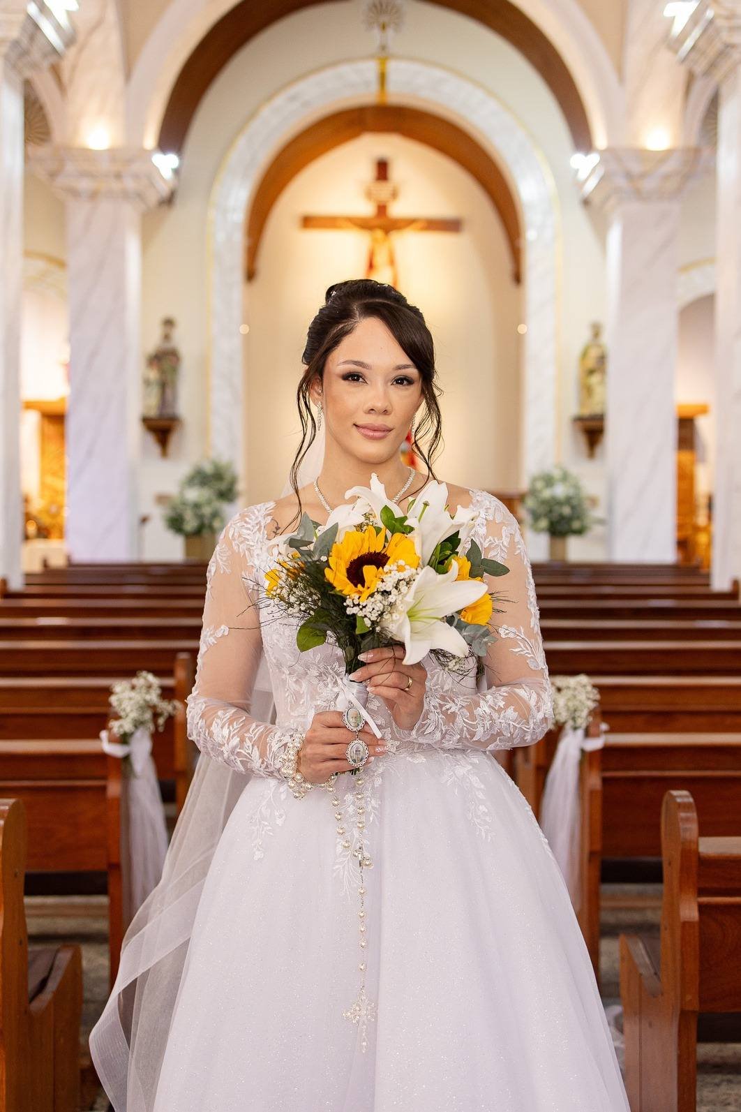 Noiva com buquê de girassóis no corredor central da igreja