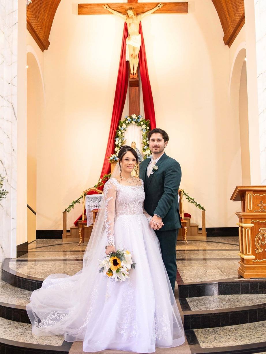 Noivos no altar de uma capela, noiva com buquê de girassóis